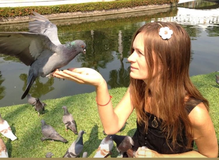 Woman smiling and releasing pigeons by a pond — spiritual connection to animals and free about Southern California Pet Sitting