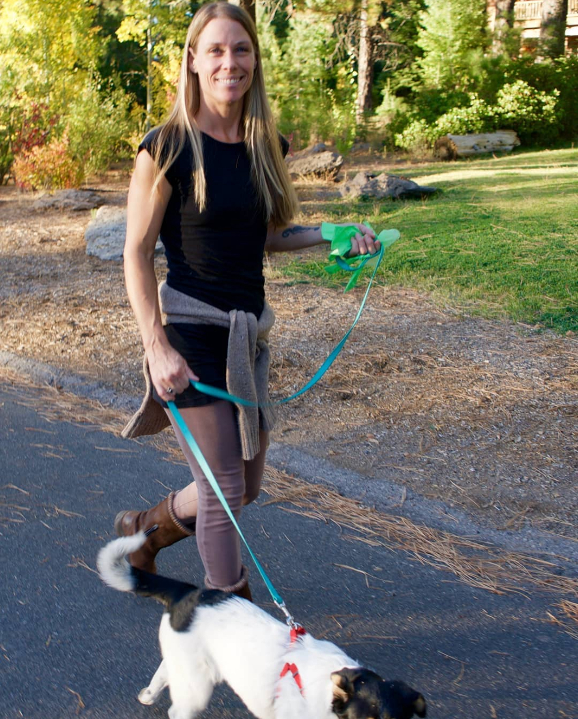 Woman in a Black top walking a Black and white dog on a neighborhood Street. Southern California Pet Sitting 